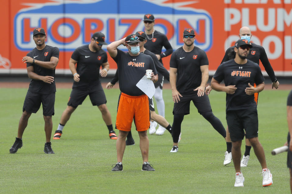 Baltimore Orioles manager Brandon Hyde, center in orange shorts, looks on as his team warms up during baseball training camp, Tuesday, July 7, 2020, in Baltimore. (AP Photo/Julio Cortez)