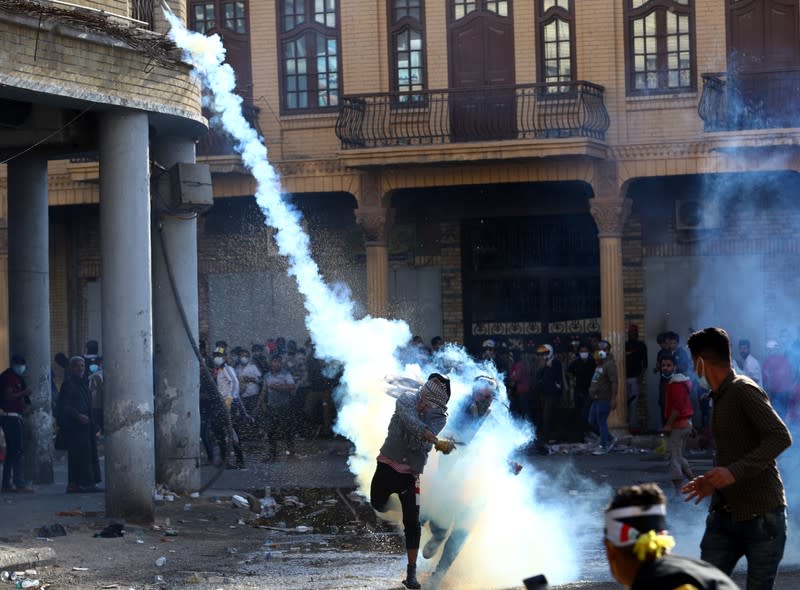 A demonstrator throws away a tear gas canister during ongoing anti-government protests in Baghdad