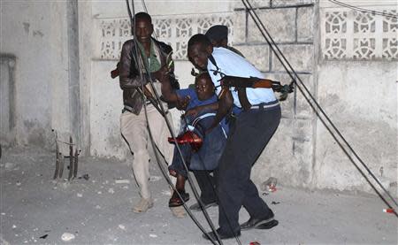 Police officers carry an injured man from the scene of a bomb attack outside the Jazira hotel in Mogadishu January 1, 2014. REUTERS/Feisal Omar