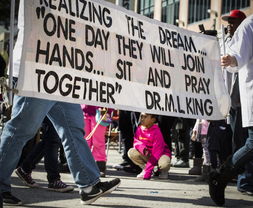 In this Monday, Jan. 15, 2018 photo, a quote from Dr. Martin Luther King, Jr., is carried during The "Original" MLK, Jr. Parade in Houston. For more than two decades, competing MLK Day parades have been held in Houston. This year, the city of Houston threw its official support behind one parade, the 41st annual “Original” MLK, Jr. Parade, hoping the city could unite behind only one parade. But organizers of the other parade, the 25th annual MLK Grande Parade, will still be holding its event and they say they have no plans to stop having their own parade. (Brett Coomer /Houston Chronicle via AP)