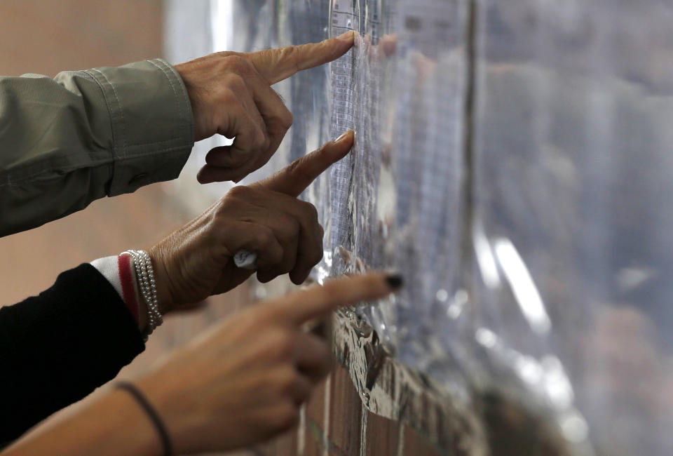 Voters check a list to confirm where they should cast their ballots during legislative elections in Bogota, Colombia, Sunday, March 9, 2014. Colombia's former President Alvaro Uribe is running for senator for the Democratic Center Party. (AP Photo/Fernando Vergara)