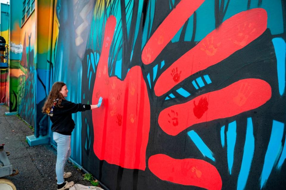Jurni Montiel, 14, one of the Native youth artists, adds her handprint to a red hand on a Miwok Middle School mural during an unveiling ceremony on Saturday celebrating the school’s historic name change from Sutter Middle School. The red hand print is meant to raise awareness of the national crisis of missing and murdered Indigenous women. Lezlie Sterling/lsterling@sacbee.com