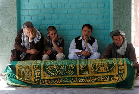 Afghans sit beside the coffin of Afghan journalist Zabihullah Tamanna, before a burial ceremony, in Kabul, Afghanistan June 7, 2016. REUTERS/Omar Sobhani