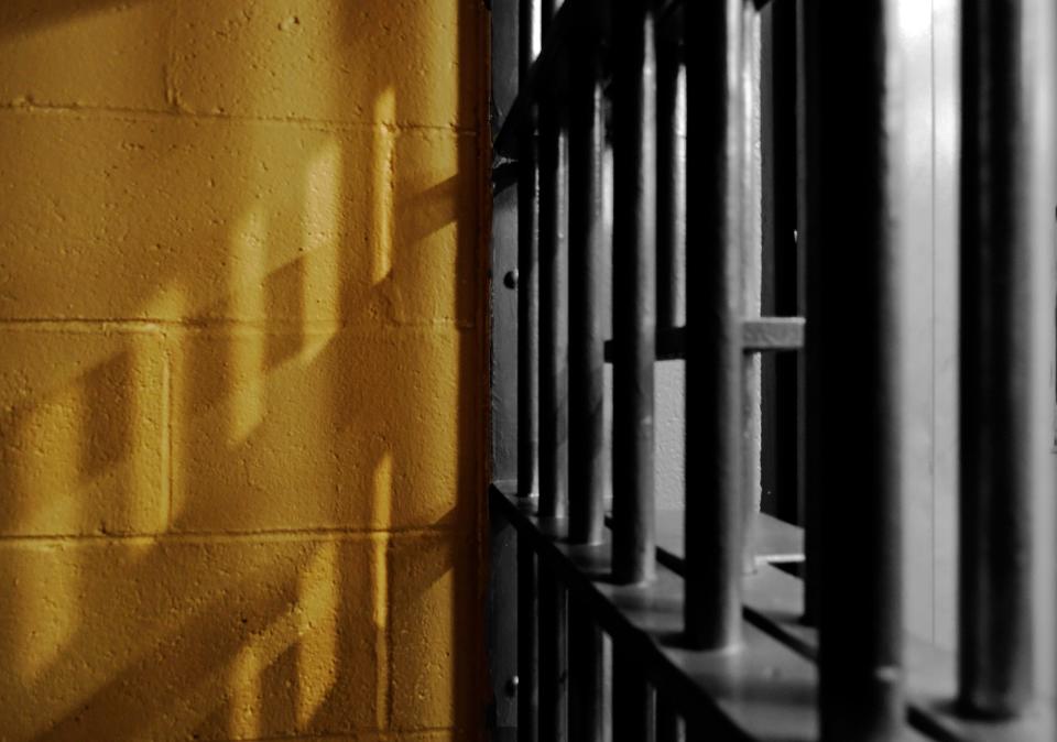 Shadows on a wall of a jail cell from the barred door