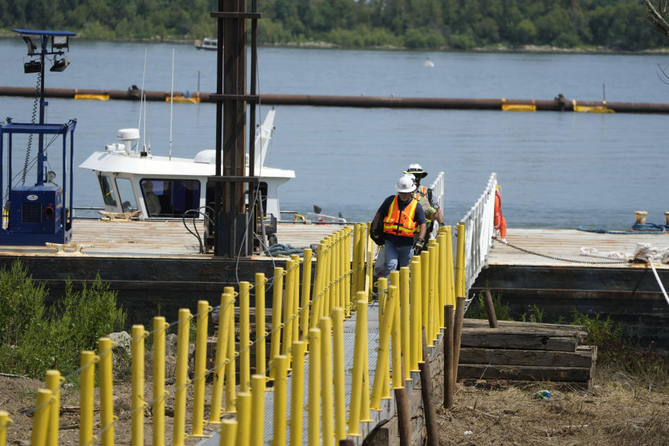 Workers disembark a boat where sills are being made in the Mississippi River to help limit salt water intrusion that is progressing upriver due to the unusually low water level in the river in Plaquemines Parish, La., Monday, Sept. 25, 2023. (AP Photo/Gerald Herbert)