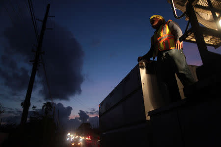 A worker of Puerto Rico's Electric Power Authority (PREPA) looks at his colleagues (not pictured) as they repair part of the power grid after Hurricane Maria hit the area in September, in Manati, Puerto Rico October 30, 2017. REUTERS/Alvin Baez