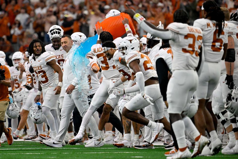 Texas players douse coach Steve Sarkisian after the Longhorns' win over Oklahoma State in the Big 12 championship game Dec. 2. The former Alabama offensive coordinator led Texas to its first College Football Playoff berth in his third season in Austin.
