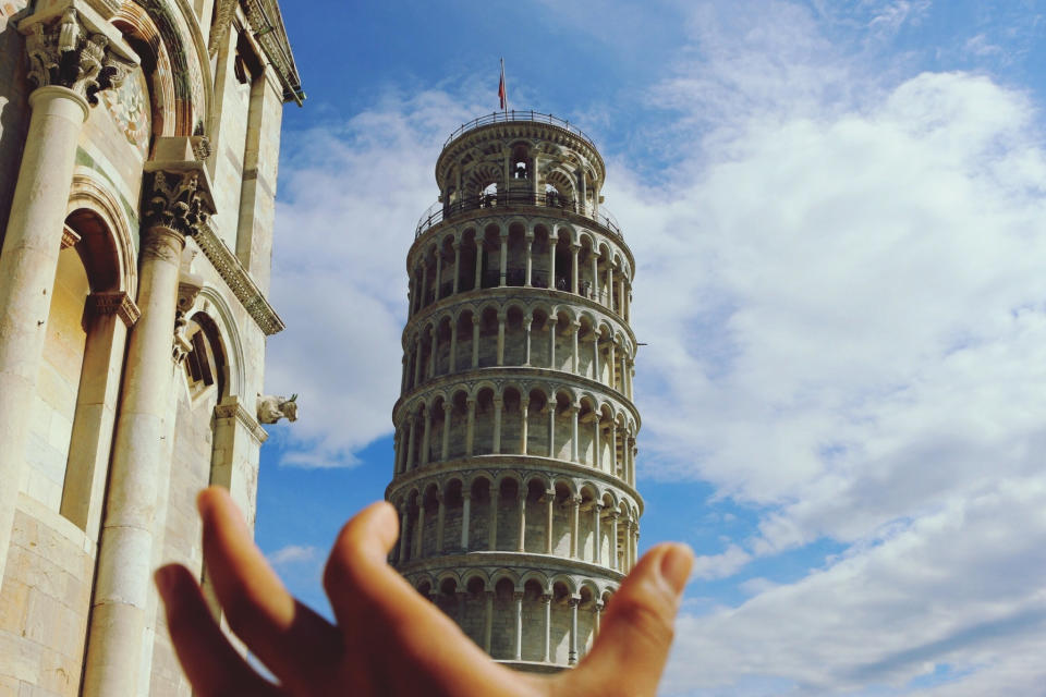 A hand "holding" the Leaning Tower of Pisa.