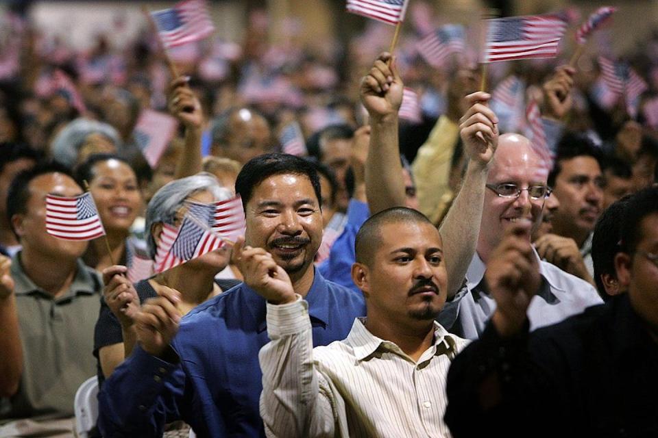 A crowd celebrates after being sworn in as U.S. citizens at a naturalization ceremony in 2007 in California. <a href="https://www.gettyimages.com/detail/news-photo/immigrants-wave-flags-after-being-sworn-in-as-u-s-citizens-news-photo/75710241?adppopup=true" rel="nofollow noopener" target="_blank" data-ylk="slk:David McNew/Getty Images;elm:context_link;itc:0;sec:content-canvas" class="link ">David McNew/Getty Images</a>