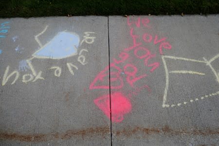 "We Love You God" is written in chalk on a sidewalk in front of a church in Saginaw Township