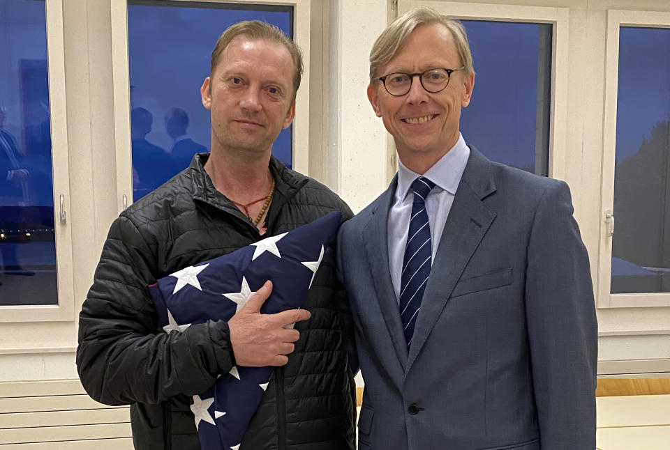 In this image provided by the U.S. State Department, Michael White holds an American flag as he poses for a photo Thursday, June 4, 2020, with U.S. special envoy for Iran Brian Hook at the Zurich, Switzerland, airport after White’s release from Iran. White, a Navy veteran who's been detained in Iran for nearly two years has been released and is making his way home, with the first leg on a Swiss government aircraft. (U.S. State Department via AP)