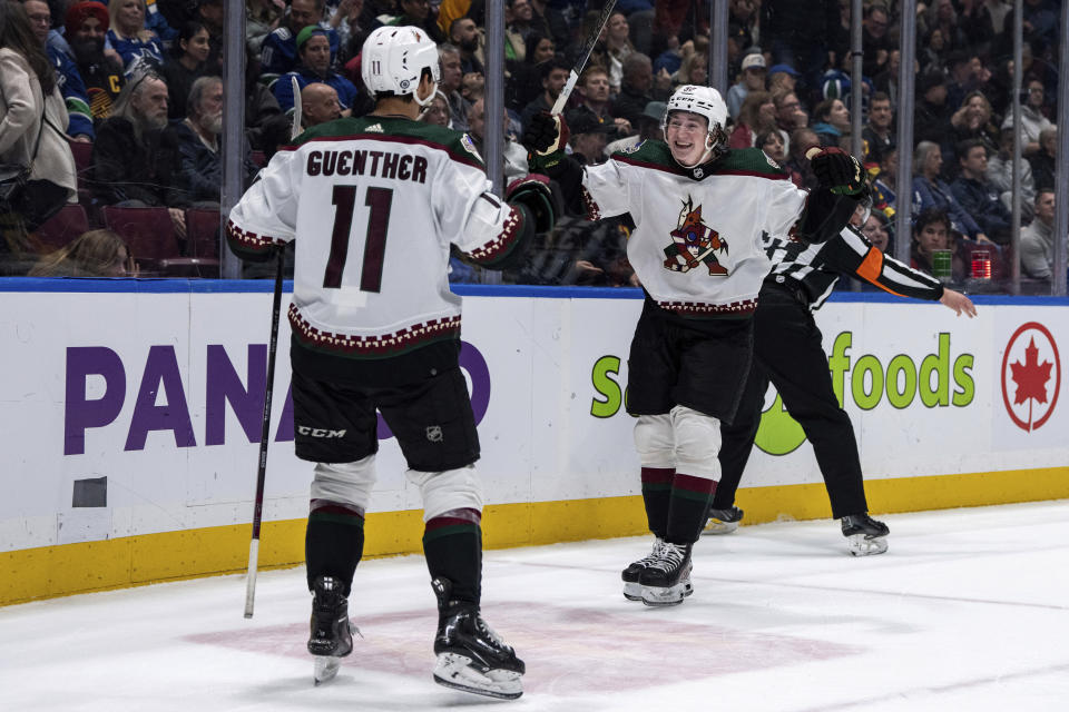 Arizona Coyotes' Dylan Guenther (11) celebrates with Logan Cooley (92) after scoring against the Vancouver Canucks during overtime in an NHL hockey game Wednesday, April 10, 2024, in Vancouver, British Columbia. (Ethan Cairns/The Canadian Press via AP)