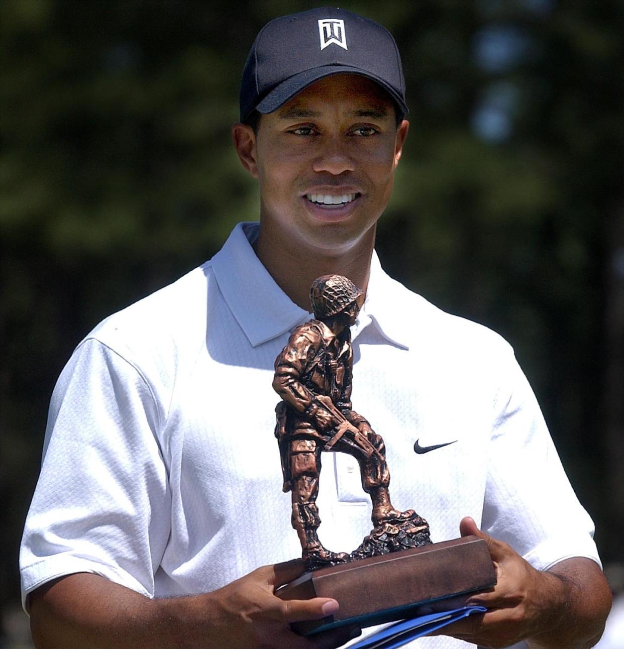 PGA golfer Tiger Woods holds a bronze statue of Iron Mike that was given to him during a 2004 Tiger Woods Foundation Junior Golf Clinic & Exhibition at Stryker Golf Course on then- Fort Bragg.