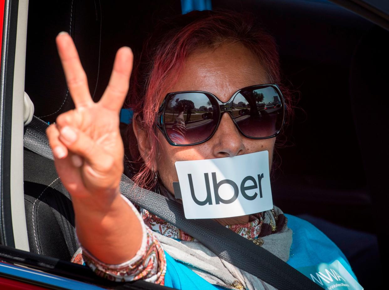 A protester gestures as Uber and Lyft drivers drive through Beverly Hills on their way to demonstrate outside the recently purchased $72 million home of Uber co-founder Garrett Camp, to protest the first day of an "IPO cash out" in Beverly Hills, California on November 6, 2019. - The drivers claim that "executives are poised to cash out their IPO billions while at the same time continuing to drive down worker pay, leaving many drivers sleeping in their cars and unable to provide for their families". (Photo by Mark RALSTON / AFP) (Photo by MARK RALSTON/AFP via Getty Images)