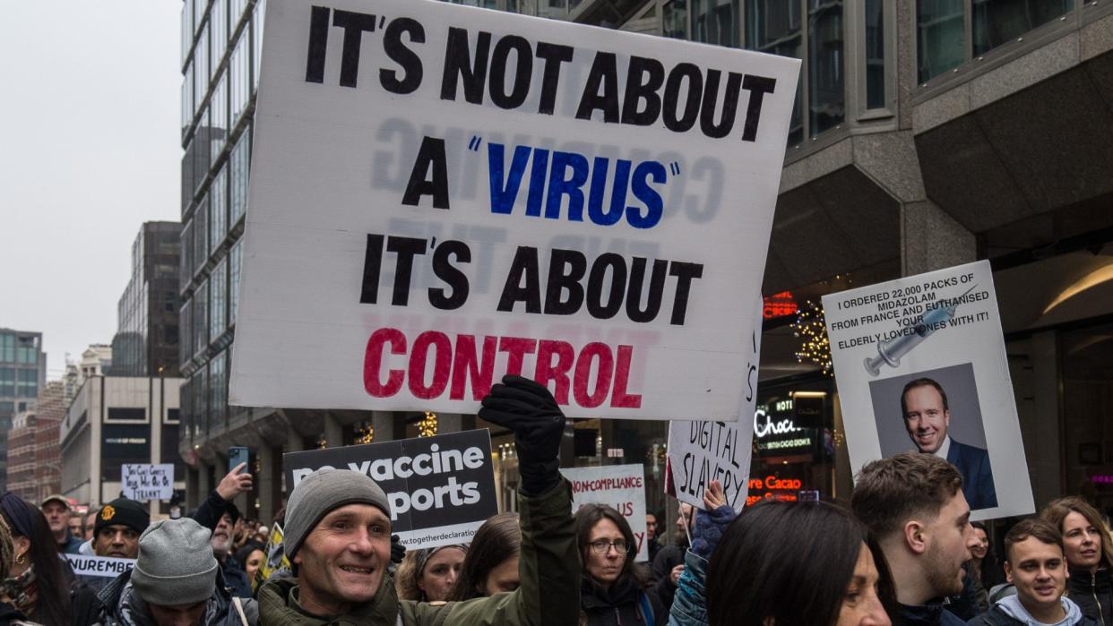  photo shows a man outdoors at a protest in London holding a sign that reads "It's not about a 'virus,' it's about control." 