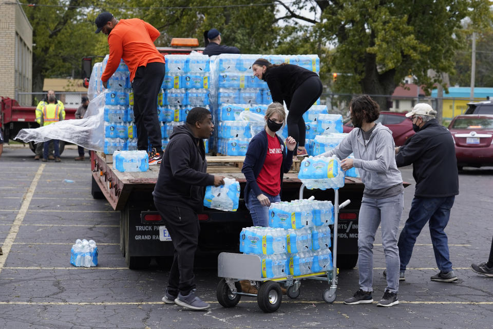 FILE - Volunteers prepare bottled water to be distributed to residents at the local high school parking lot Oct. 21, 2021, in Benton Harbor, Mich. Lead pipes have caused harm for decades. In recent years, residents in Newark, N.J., and Benton Harbor, were forced to use bottled water for basic needs like cooking and drinking, after tests revealed elevated levels of lead. (AP Photo/Charles Rex Arbogast, File)