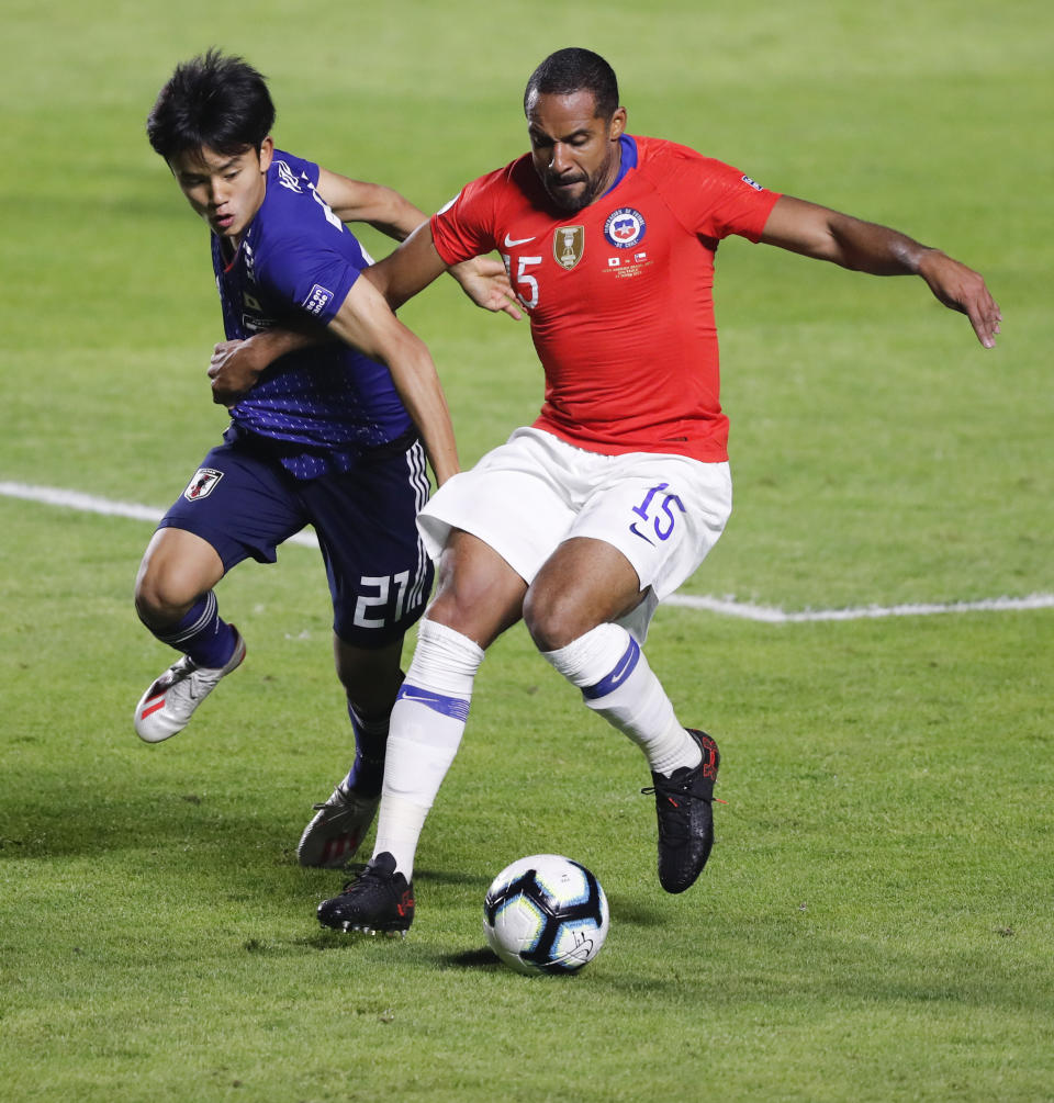Japan's Takefusa Kubo, left, and Chile's Jean Beausejour, compete for the ball during a Copa America Group C soccer match at the Morumbi stadium in Sao Paulo, Brazil, Monday, June 17, 2019. (AP Photo/Nelson Antoine)