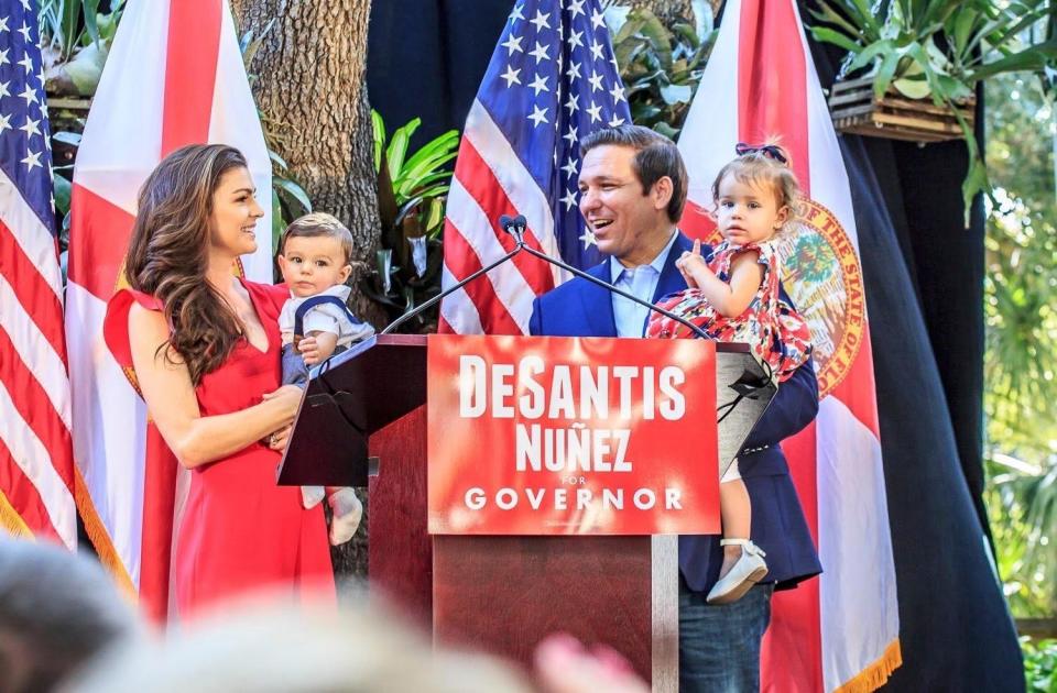 Ron DeSantis and Casey DeSantis at a campaign event, each holding one of their children