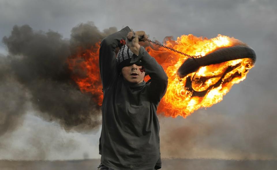 In this photo taken on Sunday, March 10, 2019, a boy spins a burning tire on a metal chain, during a ritual marking the upcoming Clean Monday, the beginning of the Great Lent, 40 days ahead of Orthodox Easter, on the hills surrounding the village of Poplaca, in central Romania's Transylvania region. Romanian villagers burn piles of used tires then spin them in the Transylvanian hills in a ritual they believe will ward off evil spirits as they begin a period of 40 days of abstention, when Orthodox Christians cut out meat, fish, eggs, and dairy. (AP Photo/Vadim Ghirda)