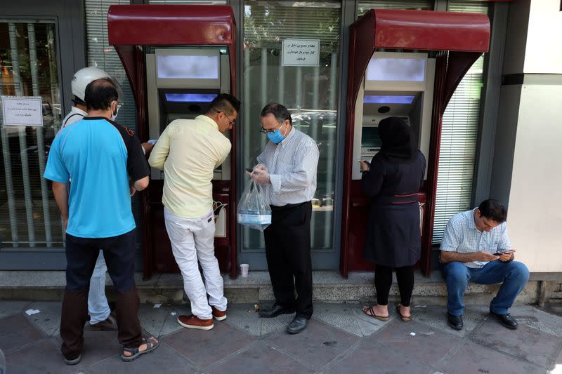 People stand in front of ATM machines to get money at Ferdowsi square in Tehran