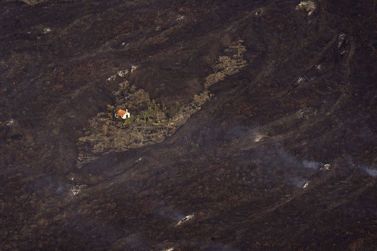 La lava de la erupción de un volcán rodea una casa en la isla de La Palma en Canarias, España, el jueves 23 de septiembre de 2021