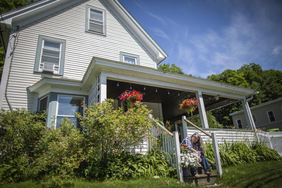 Lisa Edson Neveu, 52, cuts flowers in front of her house in Montpelier, Vt., that was damaged by the 2023 flood, July 3, 2024. A year after catastrophic flooding inundated parts of Vermont, some homeowners are still in the throes of recovery. AP Photo/ Dmitry Belyakov)