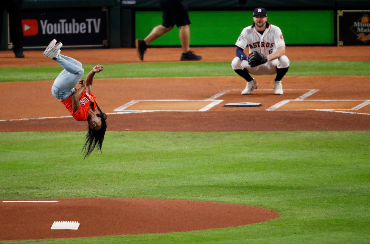 Gymnast Simone Biles performs a flip after throwing out the ceremonial first pitch prior to Game 2 of the  World Series between the Houston Astros and the Washington Nationals at Minute Maid Park on Wednesday in Houston.