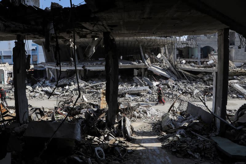 Palestinians walk past destroyed houses, in Jabalia refugee camp