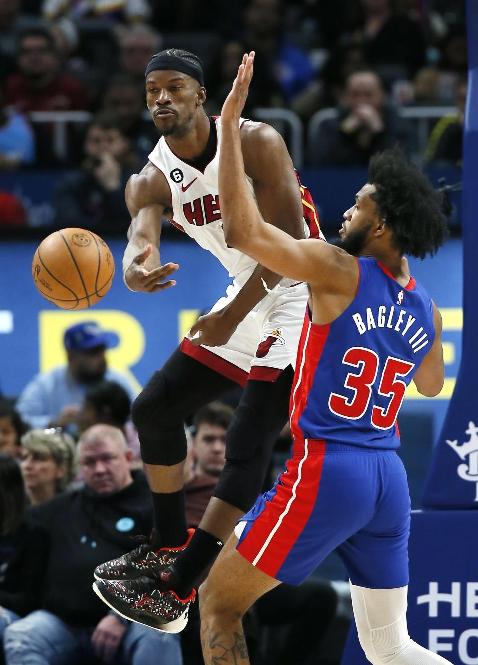 Miami Heat forward Jimmy Butler, left, passes the ball against Detroit Pistons forward Marvin Bagley III (35) during the first half of an NBA basketball game, Sunday, March 19, 2023, in Detroit. (AP Photo/Duane Burleson)