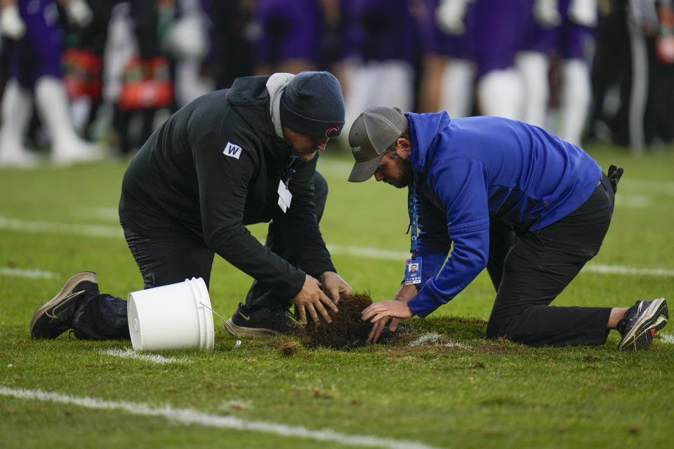 Workers rush to fix a hole in the field during the first half of an NCAA college football game between Iowa and Northwestern, Saturday, Nov. 4, 2023, at Wrigley Field in Chicago. (AP Photo/Erin Hooley)