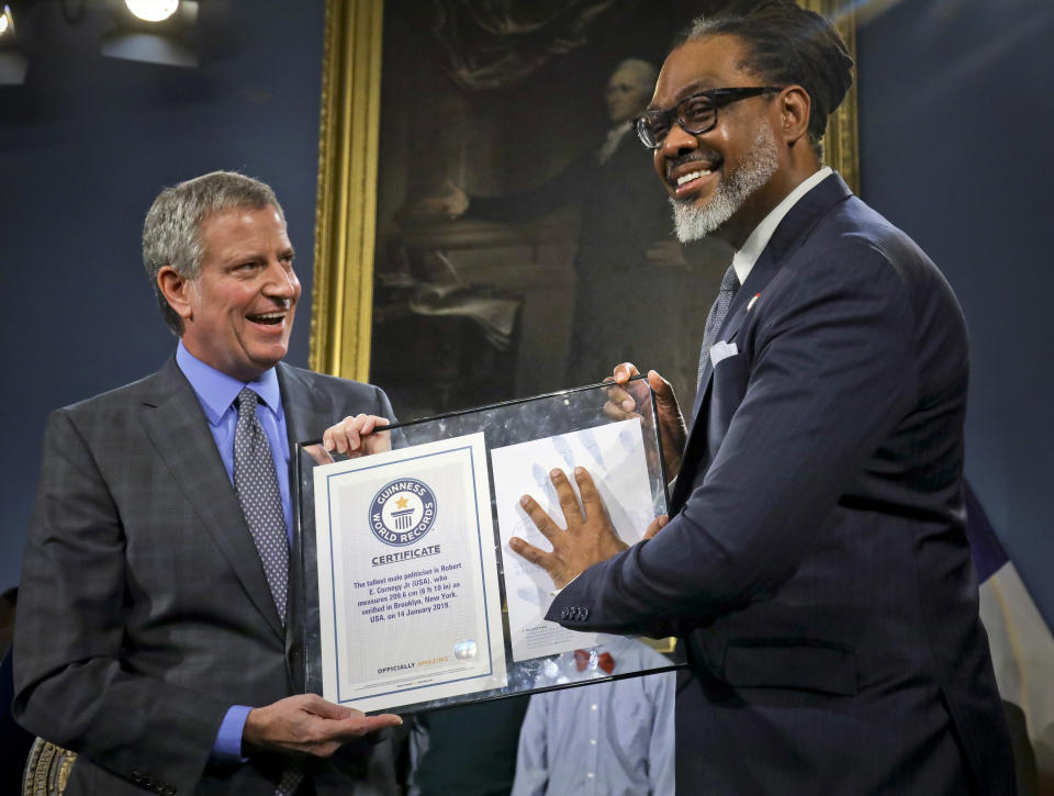 New York Mayor Bill de Blasio, left, awards N.Y. City Councilman Robert Cornegy, Jr. the Guinness World Record's tallest male politician, Wednesday March 27, 2019, at City Hall in New York. (AP Photo/Bebeto Matthews)