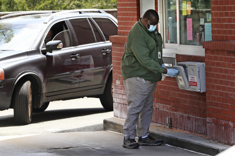 An employee from Quest Diagnostics looks inside the COVID-19 virus test collection box at a drive thru for the CVS Pharmacy in Danvers, Mass., Friday, May 15, 2020. CVS has expanded their testing sites. (AP Photo/Charles Krupa)