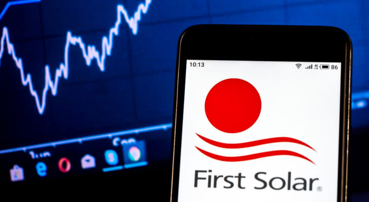 First Solar logo on smartphone in front of computer screen with graphs. FSLR stock