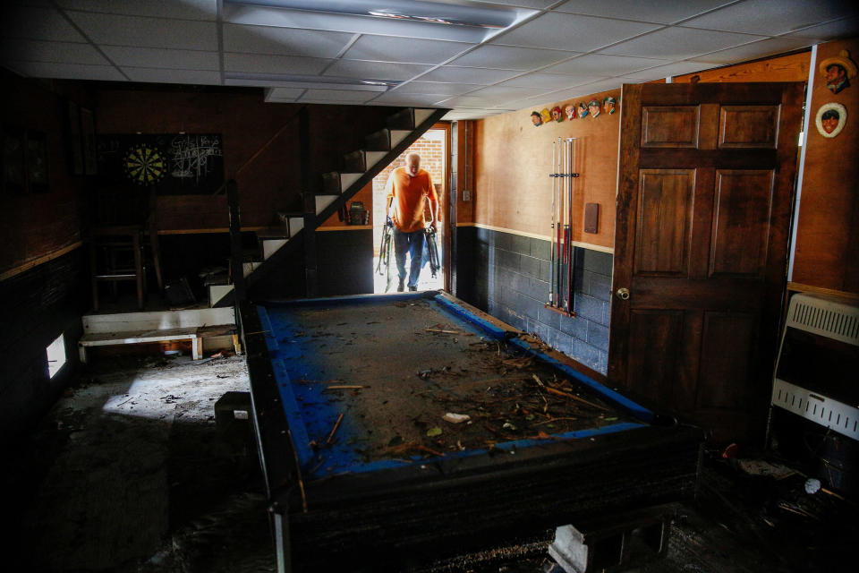 A man removes debris and items from a house in New Bern.