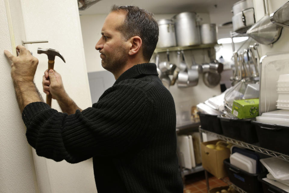 In this Monday, Oct. 8, 2012 photo, Anthony Cavallo, owner of the restaurant Vintage 50, mounts a potato cutter in his restaurant in Leesburg, Va. Cavallo, who does much of his own maintenance in his restaurant, says lingering questions about the economic future hurt business. He closed two restaurants in the last year. (AP Photo/Jacquelyn Martin)