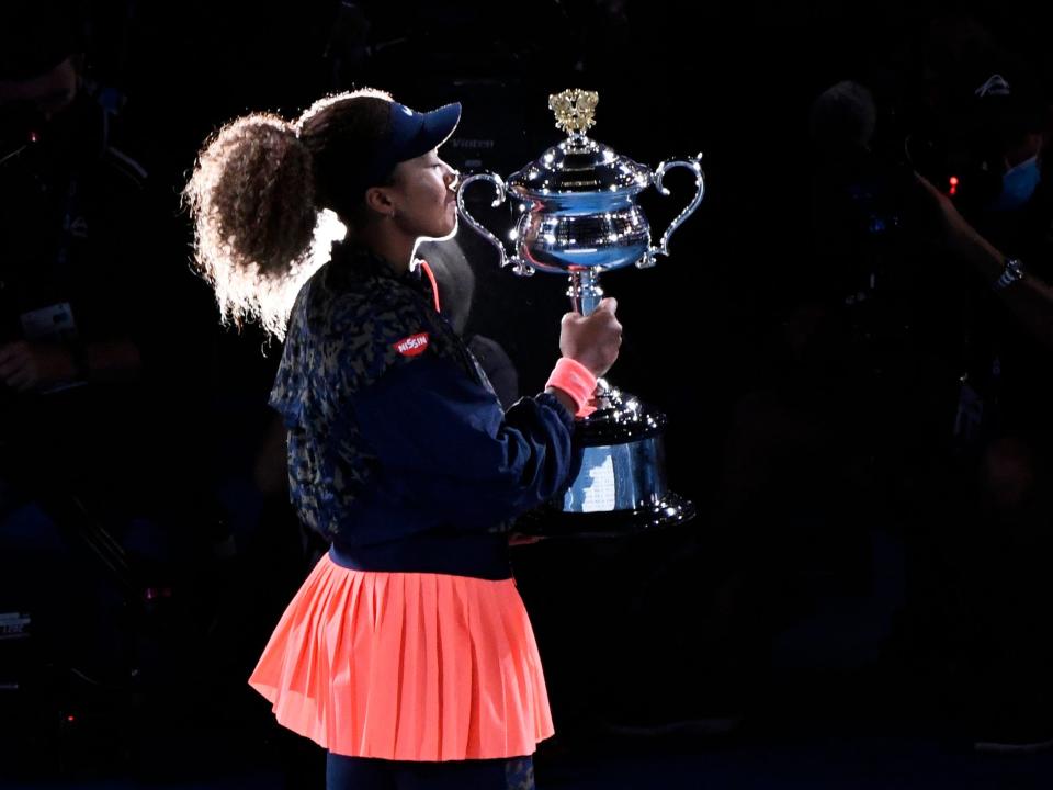 Naomi Osaka kisses her Australian Open trophy.