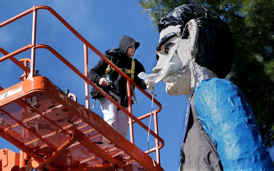 Jason Campbell, an employee of the paint and sign shop for the Illinois State Fairgrounds takes the mask off the Abraham Lincoln figure at the fairgrounds Wednesday, April 6, 2022. The mask has been on the statue since September 2020 as part of the All in Illinois COVID-19 public awareness campaign. [Thomas J. Turney/State Journal-Register]