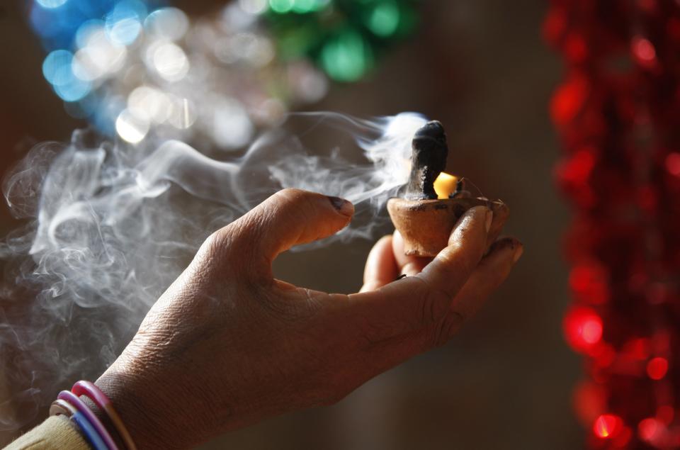 A Hindu woman devotee lights earthen lamps as she prays at the Aap Shambhu Lord Shiva temple during "Shivaratri" festival in Jammu, India, Tuesday, Feb.17, 2015. 