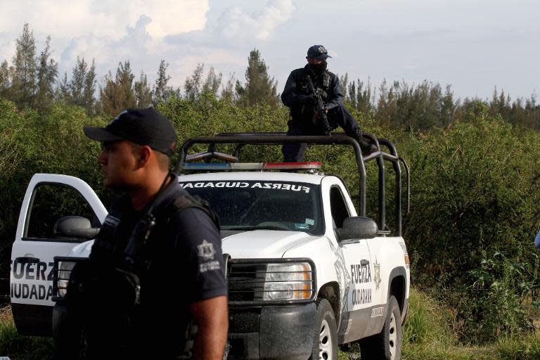 State policemen stand guard at the entrance of the ranch where gunmen took cover during an intense gun battle with the police, along the Jalisco-Michoacan highway in Vista Hermosa, Michoacan State on May 22, 2015