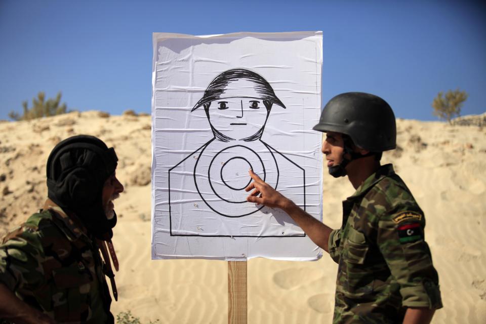 A trainee soldier from the Libyan army speaks with a commander in front of a shooting target during his graduation exam in Geminis