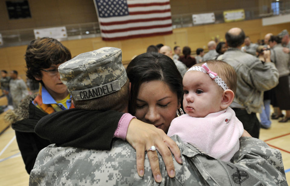 Sgt. Joseph Crandell of the U.S. 1st Armored Divison holds his seven month old daughter Lena for the first time as he hugs his wife Layla during a welcome home ceremony at the home base in Wiesbaden, Germany, November 25, 2008. The soldiers of the 1st AD returned on Tuesday from a 15month deployment to Iraq. REUTERS/Kai Pfaffenbach (GERMANY)