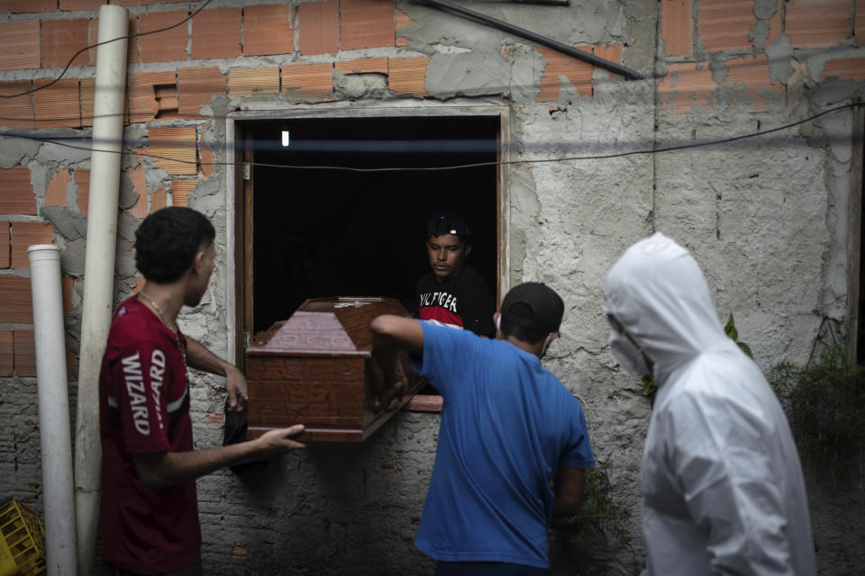 Familiares ayudan a un trabajador de SOS Funeral, vestido con un traje de protección durante el brote de coronavirus, a sacar el cuerpo de Eldon Cascais de su casa, en Manaos, Brasil, el 9 de mayo de 2020. Según los familiares de Cascais, padecía cáncer de pulmón y murió en su casa tras sufrir problemas respiratorios, tos y fatiga durante una semana. (AP Foto/Felipe Dana)