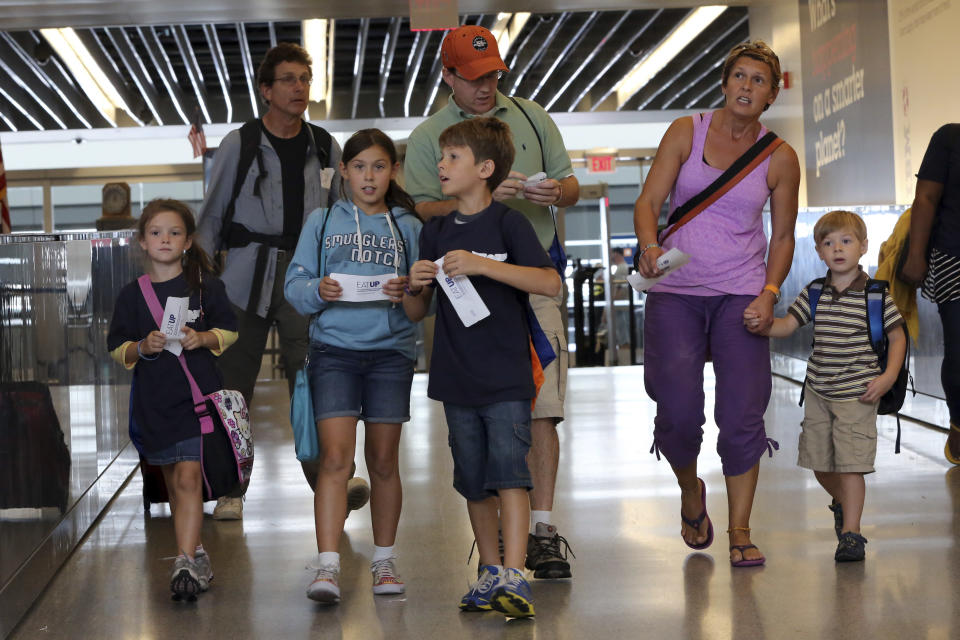 Tom Price, center, and his wife Zsuzsa, center, walk to the gate with their children, from left, Keira, 6, Hailye, 10, Owen, 9, and Callum, 4, at the JetBlue counter, Saturday, Sept. 21, 2013 at JFK airport in New York. Dozens of families with children with autism have practiced air travel at New York's Kennedy International Airport. JetBlue Airways and the nonprofit Autism Speaks held the practice run for families at JFK on Saturday. (AP Photo/Mary Altaffer)