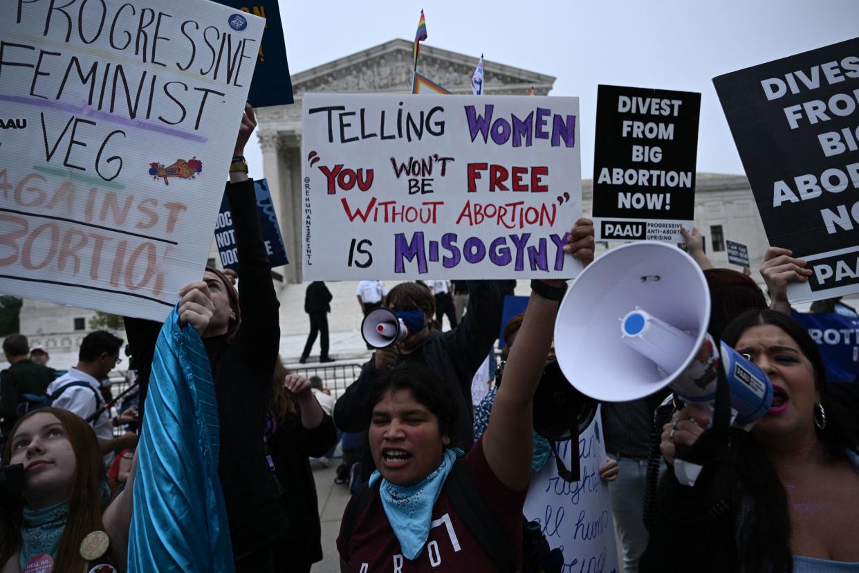 Demonstrators hold signs reading: Divest from Big Abortion now.