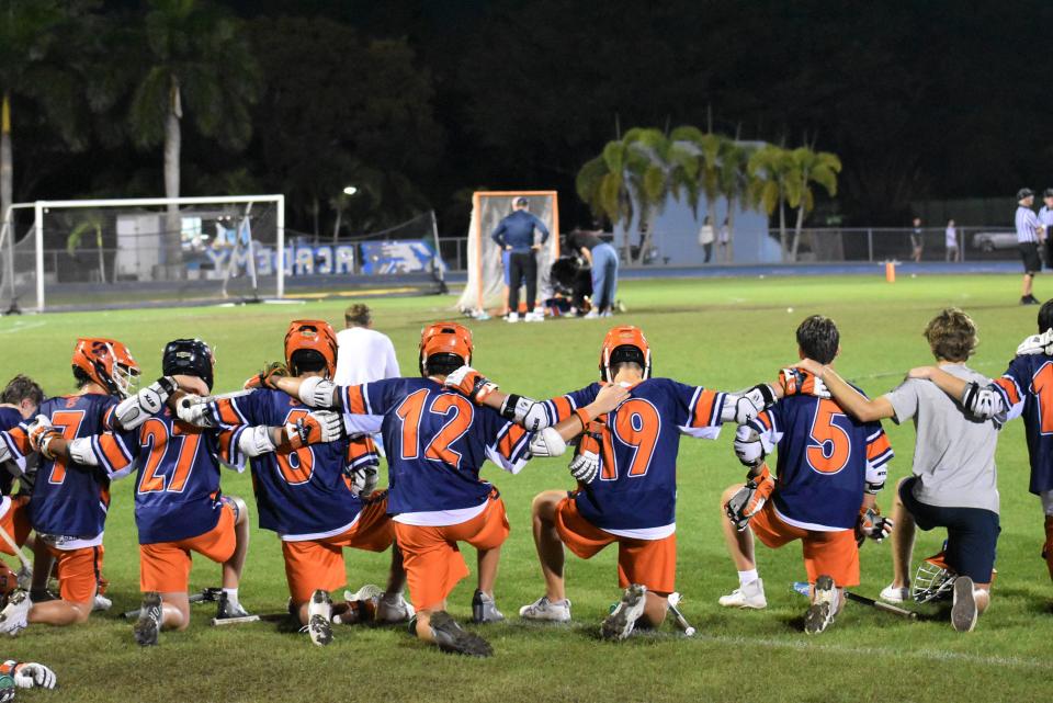 Benjamin lacrosse players lock arms as they send good thoughts toward injured teammate Jayden Vega during a game against St. John Paul II on Mar. 8, 2024.