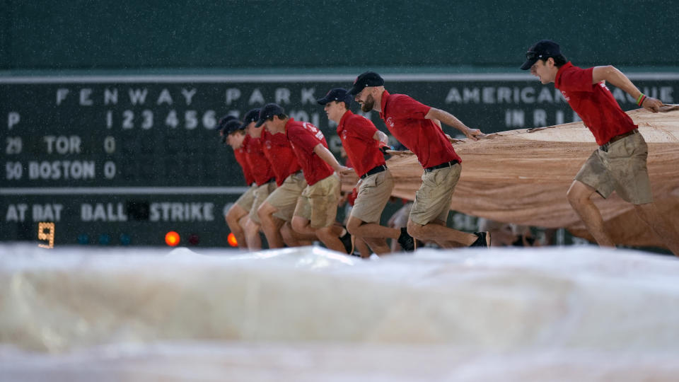 The grounds crew drags the tarp across the infield of Fenway Park during a downpour in the second inning of a baseball game between the Boston Red Sox and Toronto Blue Jays, Wednesday, June 26, 2024, in Boston. (AP Photo/Charles Krupa)