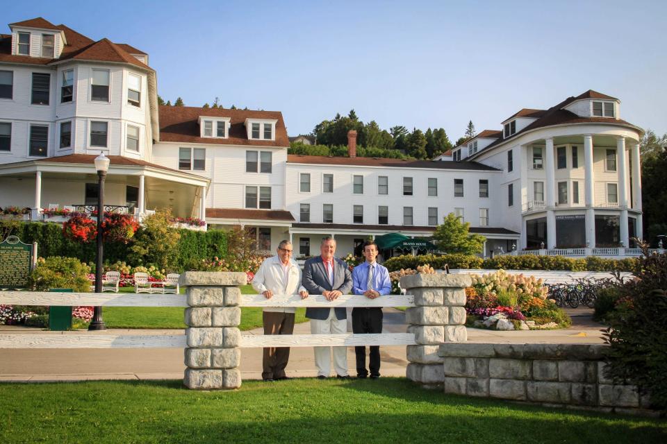 From left, Victor Callewaert, his son Todd Callewaert and grandson Andrew Callewaert, stand in front of The Island House Hotel on Mackinac Island in 2018. The Callewaerts run the hotel and six restaurants on the island as well as Ryba's Fudge Shop and a Starbucks.