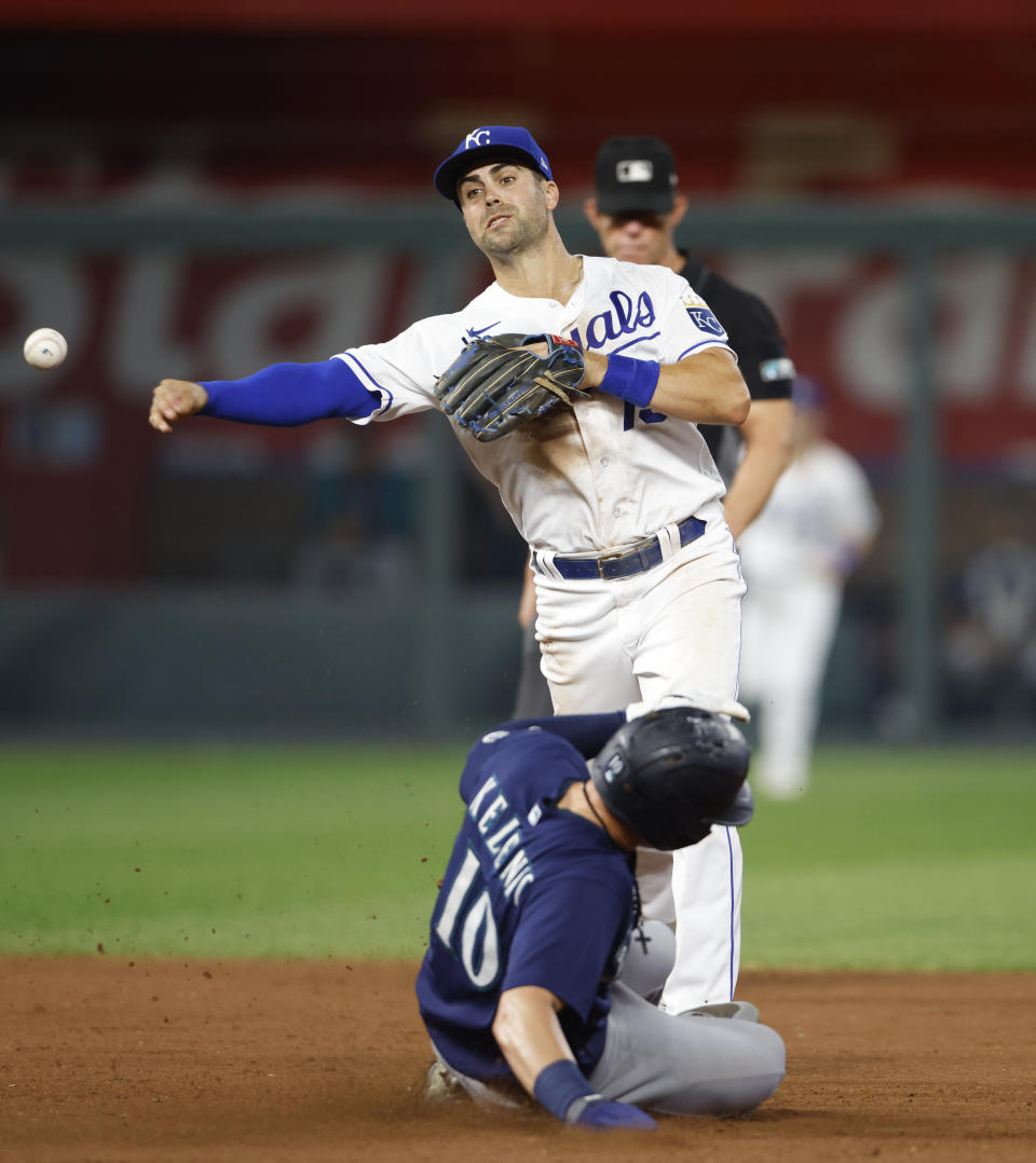 Kansas City Royals second baseman Whit Merrifield, top, throws to first base for a double play as Seattle Mariners' Jarred Kelenic (10) slides into second during the fifth inning of a baseball game at Kauffman Stadium in Kansas City, Mo., Saturday, Sept. 18, 2021. (AP Photo/Colin E. Braley)