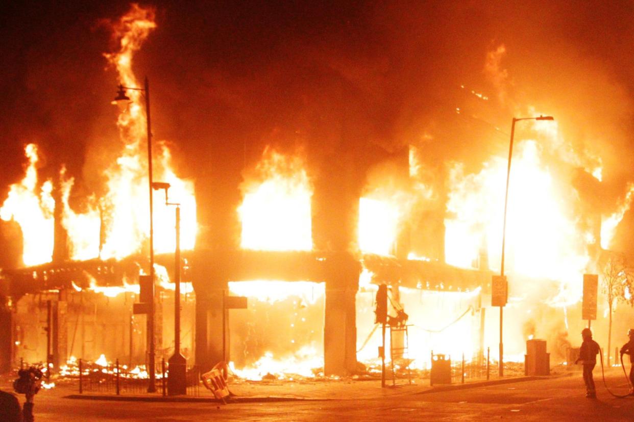 Fire fighters attempt to put out a blaze in a building in Tottenham, north London as trouble flares (PA)