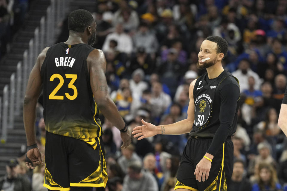 Golden State Warriors guard Stephen Curry (30) and Draymond Green (23) slap hands during the third quarter of an NBA basketball game against the New Orleans Pelicans Tuesday, March 28, 2023, in San Francisco. (AP Photo/Darren Yamashita)